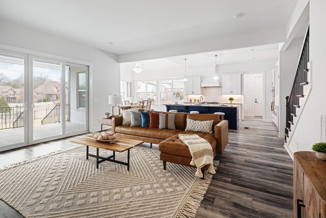 living room featuring a notable chandelier, wood-type flooring, and a healthy amount of sunlight