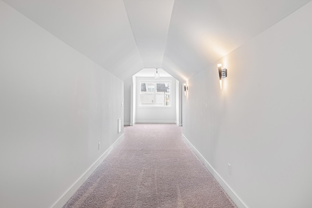 hall featuring vaulted ceiling and light colored carpet