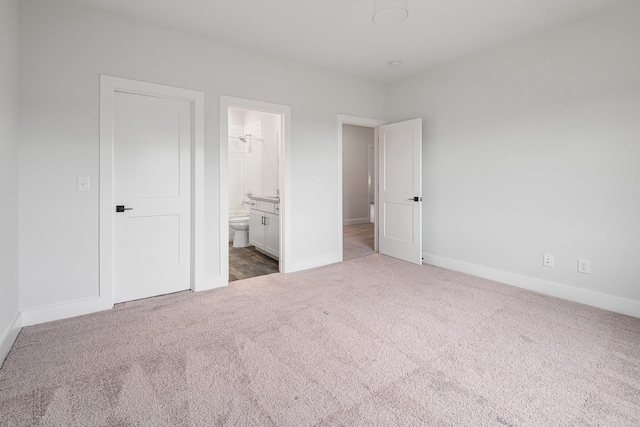 unfurnished bedroom featuring ensuite bathroom and carpet flooring