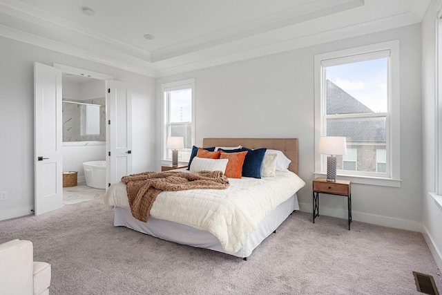 carpeted bedroom featuring ornamental molding, a raised ceiling, and ensuite bathroom