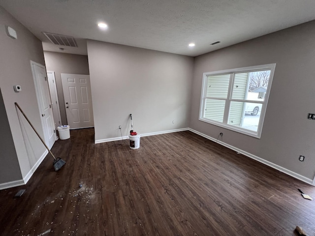 unfurnished room with a textured ceiling and dark hardwood / wood-style flooring