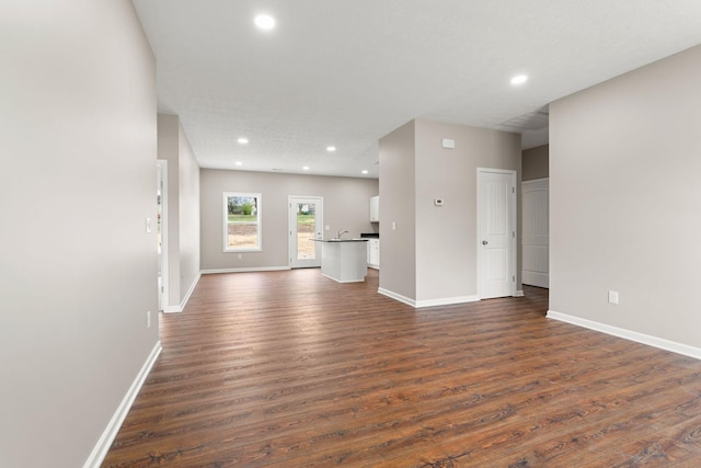 unfurnished living room featuring baseboards, recessed lighting, and dark wood-type flooring
