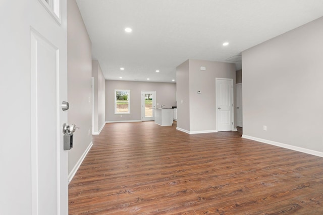 unfurnished living room with dark wood-type flooring, baseboards, and recessed lighting