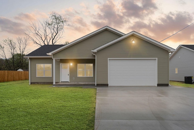 ranch-style home featuring fence, an attached garage, central AC, concrete driveway, and a front yard