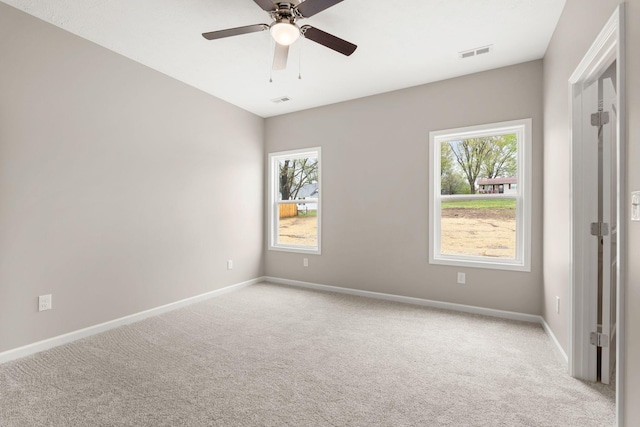 unfurnished room with light carpet, a wealth of natural light, visible vents, and baseboards