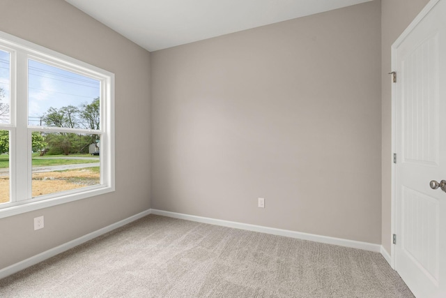 spare room with baseboards and light colored carpet