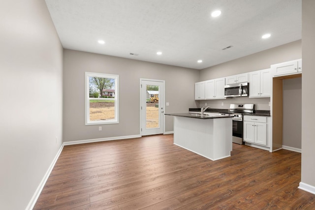 kitchen with dark wood-style floors, dark countertops, visible vents, and appliances with stainless steel finishes