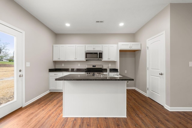 kitchen with a sink, appliances with stainless steel finishes, dark wood-style floors, visible vents, and white cabinets