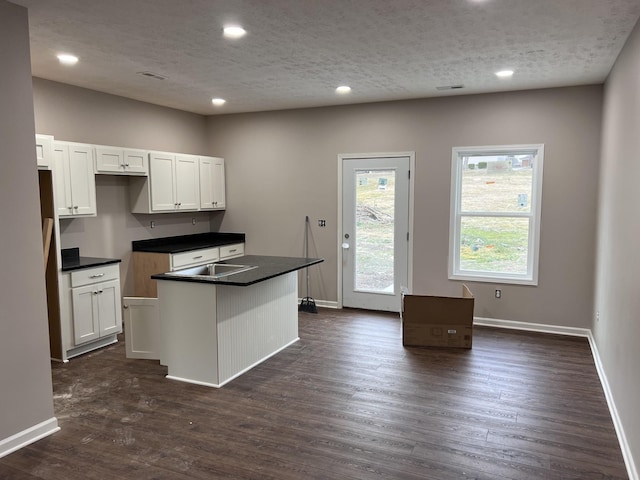 kitchen with white cabinetry, a kitchen island, dark hardwood / wood-style flooring, and a textured ceiling