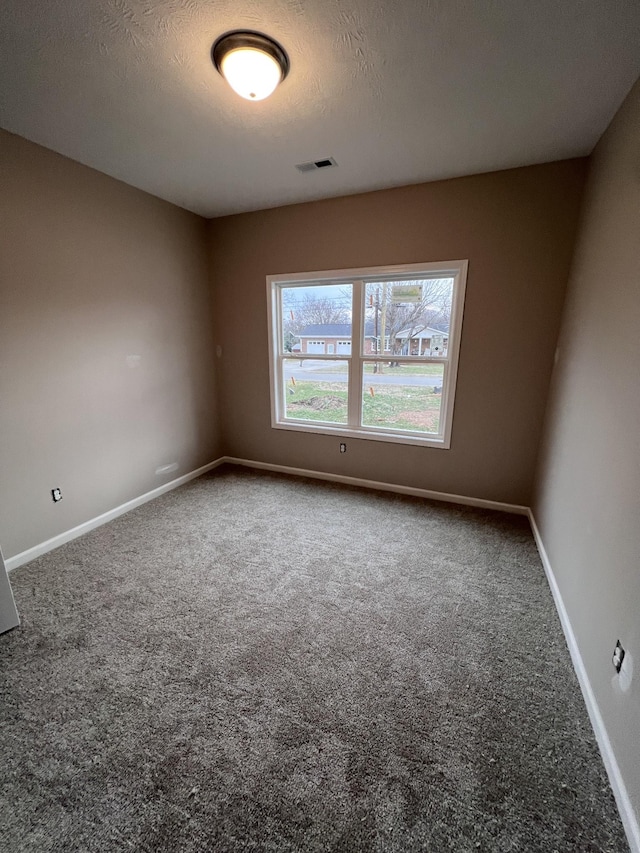 carpeted empty room with a textured ceiling