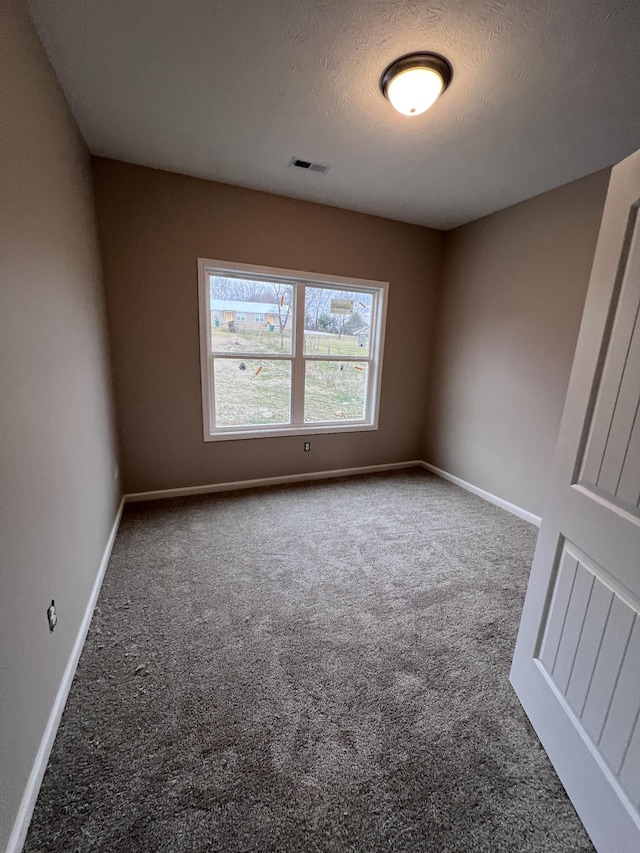 carpeted empty room with a textured ceiling