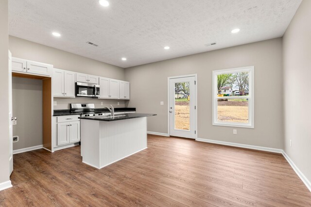 805 Shepard St S, Winchester, TN 37398 - kitchen with a center island with sink, dark countertops, white cabinets, appliances with stainless steel finishes, and wood finished floors