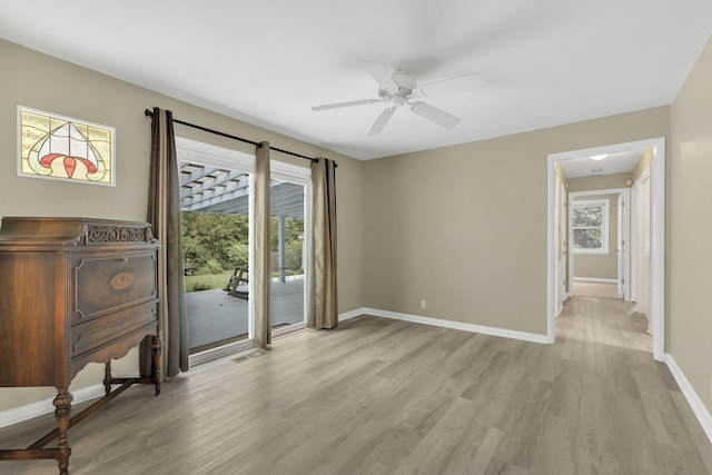 empty room with ceiling fan and light hardwood / wood-style flooring