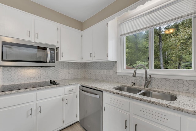 kitchen featuring sink, tasteful backsplash, light stone counters, appliances with stainless steel finishes, and white cabinets