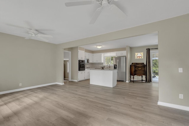 interior space with sink, light hardwood / wood-style flooring, stainless steel appliances, white cabinets, and decorative backsplash