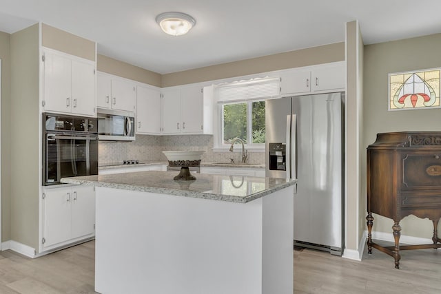 kitchen featuring black appliances, a center island, and white cabinets