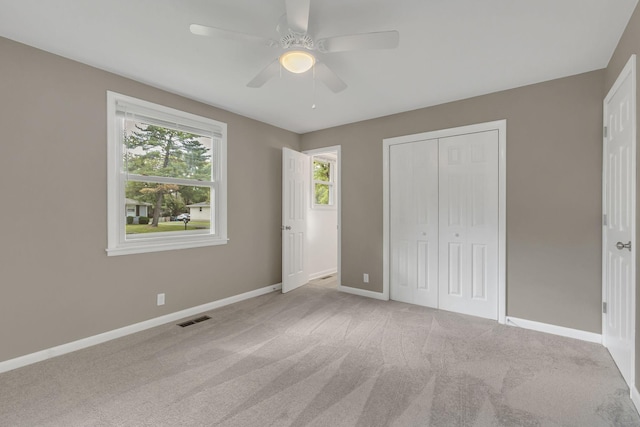 unfurnished bedroom with light colored carpet, ceiling fan, and a closet