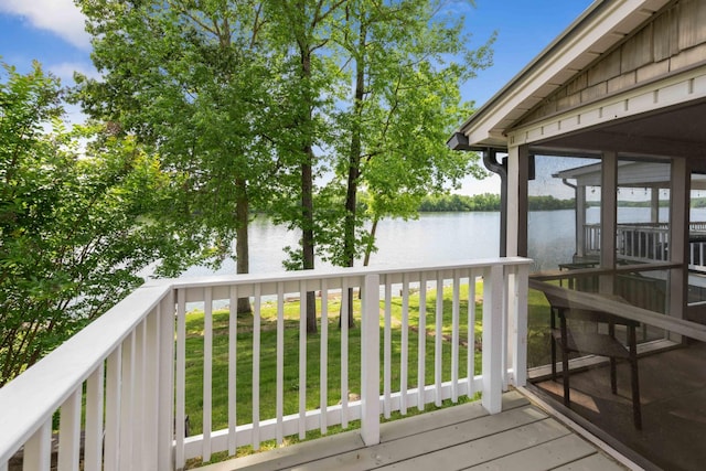 wooden deck with a water view, a yard, and a sunroom