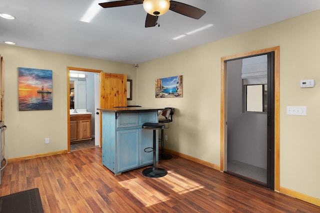 kitchen featuring dark wood-type flooring, ceiling fan, a kitchen bar, and kitchen peninsula