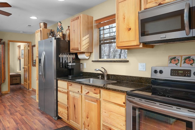 kitchen with sink, light brown cabinets, dark stone counters, and appliances with stainless steel finishes