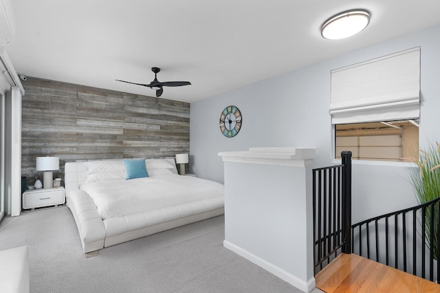 bedroom featuring wooden walls, ceiling fan, and carpet