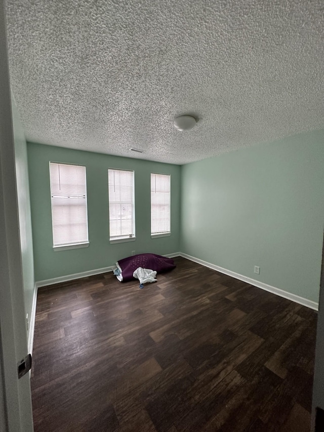 spare room featuring dark hardwood / wood-style floors and a textured ceiling