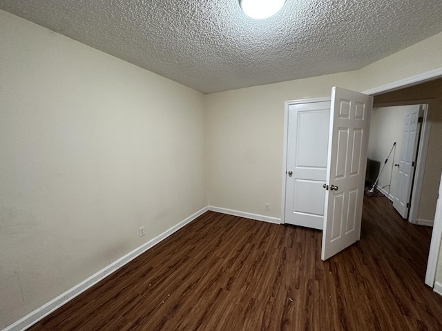 empty room featuring dark wood-type flooring and a textured ceiling