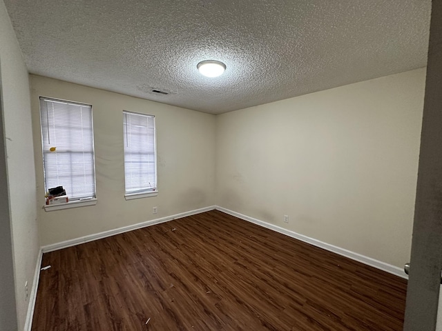 empty room with dark wood-type flooring and a textured ceiling