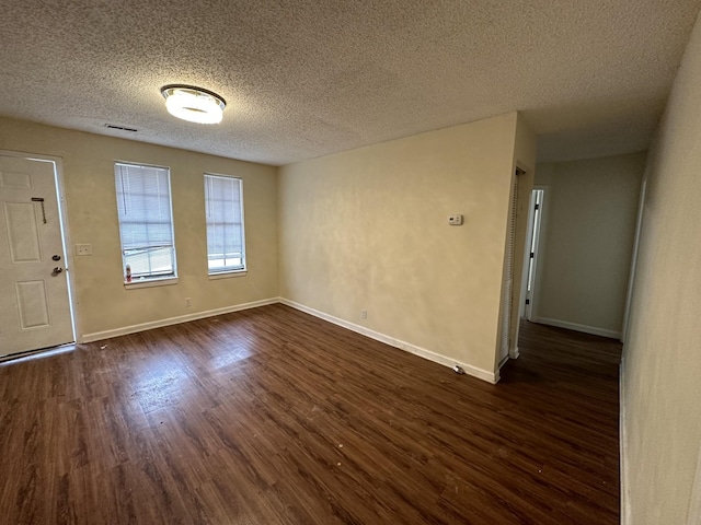 unfurnished room featuring dark wood-type flooring and a textured ceiling