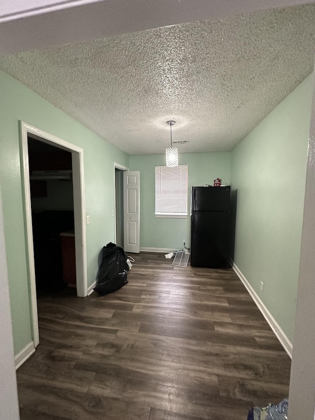 unfurnished dining area with dark hardwood / wood-style flooring and a textured ceiling