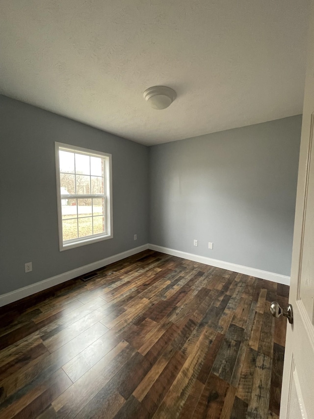 spare room with dark hardwood / wood-style flooring and a textured ceiling