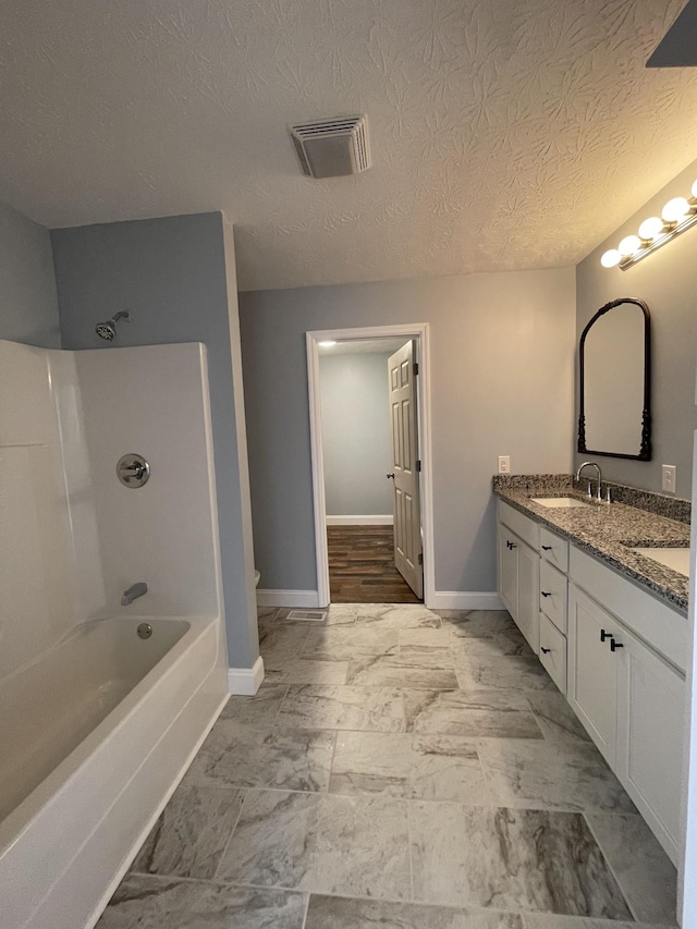 full bathroom featuring vanity, a textured ceiling, toilet, and shower / bath combination