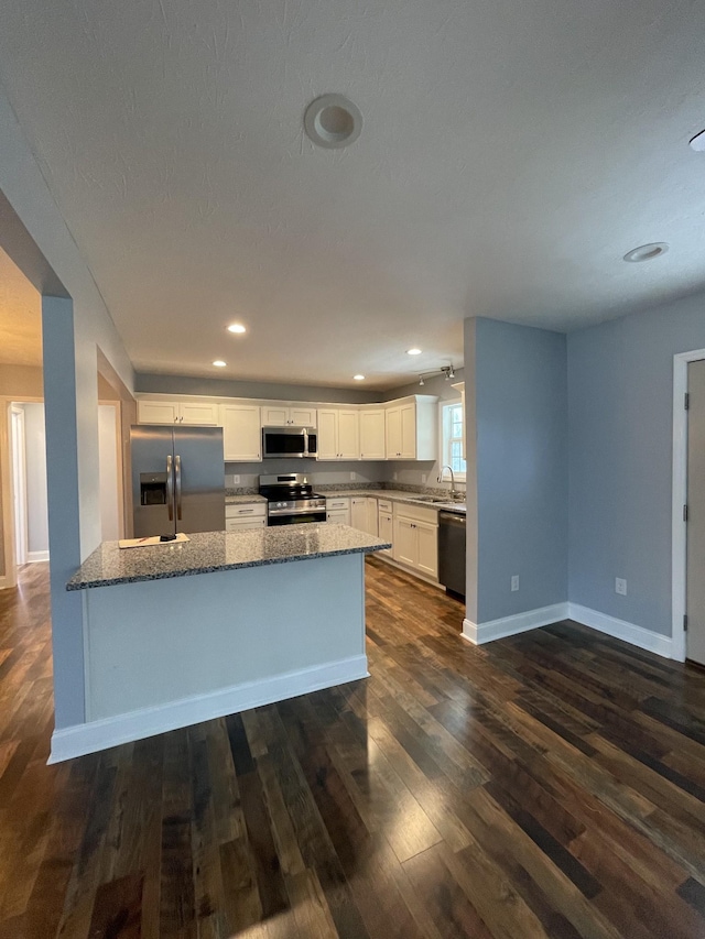 kitchen with stone counters, stainless steel appliances, sink, and white cabinets