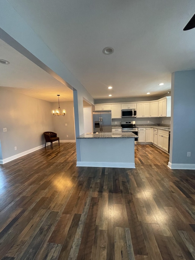 kitchen with appliances with stainless steel finishes, white cabinets, dark hardwood / wood-style flooring, and decorative light fixtures