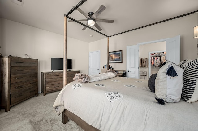 bedroom with ceiling fan, a walk in closet, a closet, and light carpet