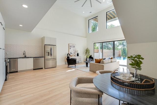 living room with sink, light wood-type flooring, and a high ceiling