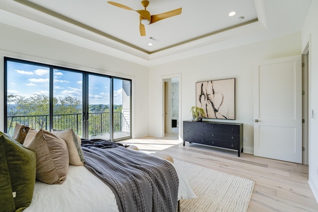 bedroom featuring access to exterior, crown molding, light hardwood / wood-style flooring, and a raised ceiling