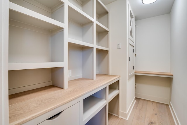 walk in closet with light hardwood / wood-style floors