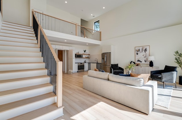 living room featuring light hardwood / wood-style floors, sink, and a towering ceiling