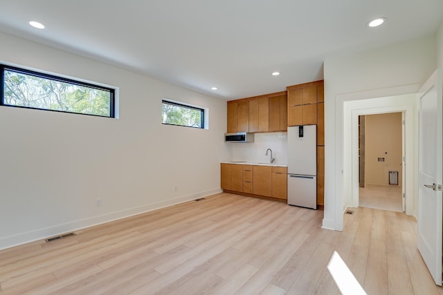 kitchen with white refrigerator and light hardwood / wood-style floors