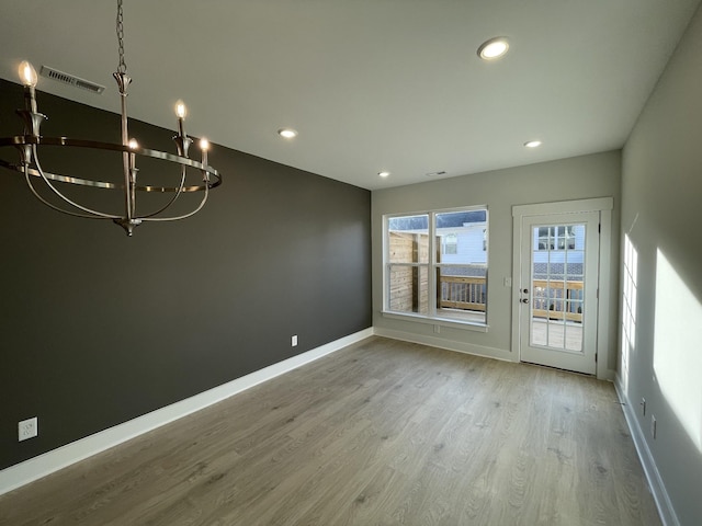 unfurnished dining area with light hardwood / wood-style flooring and a notable chandelier