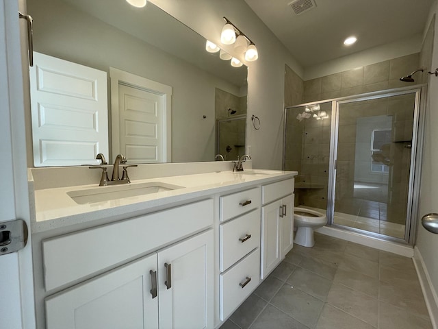 bathroom featuring a shower with door, vanity, tile patterned flooring, and toilet