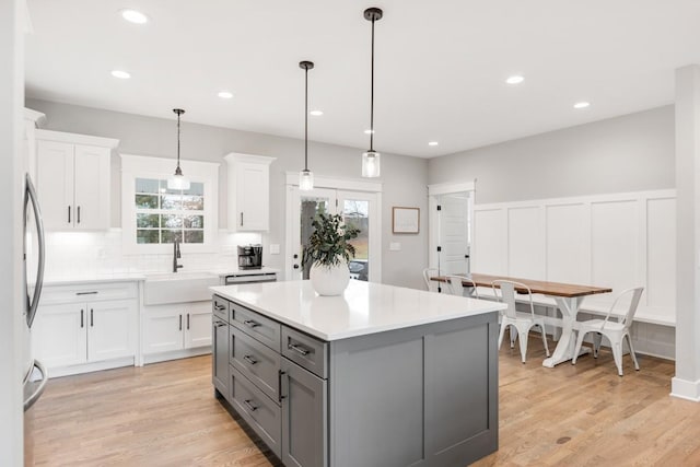 kitchen featuring a kitchen island, decorative light fixtures, white cabinetry, sink, and a healthy amount of sunlight