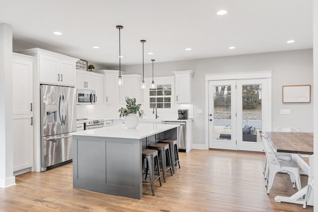 kitchen with white cabinetry, appliances with stainless steel finishes, decorative light fixtures, and a kitchen island