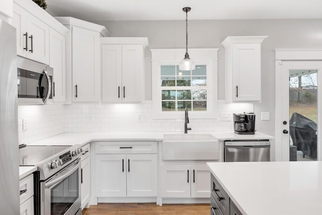 kitchen with pendant lighting, sink, appliances with stainless steel finishes, white cabinetry, and decorative backsplash