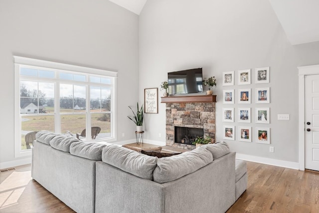 living room featuring a fireplace, high vaulted ceiling, and light wood-type flooring