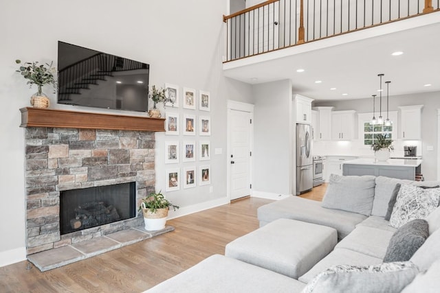 living room with a towering ceiling, a fireplace, and light hardwood / wood-style flooring