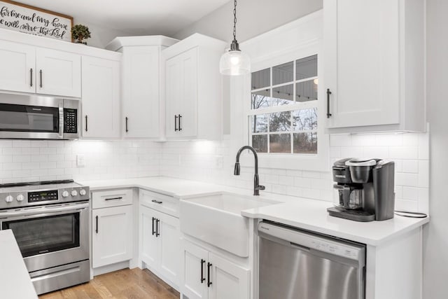 kitchen featuring white cabinetry, sink, pendant lighting, and appliances with stainless steel finishes