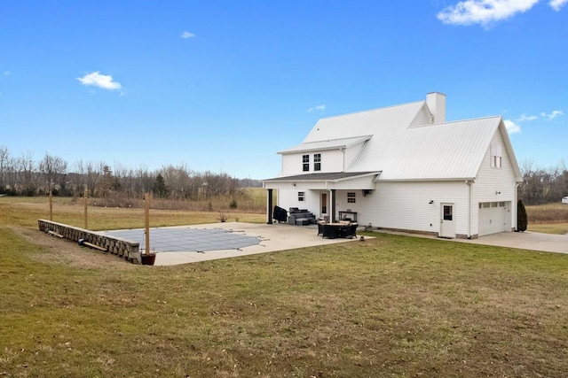 back of property featuring a garage, a yard, and a patio area