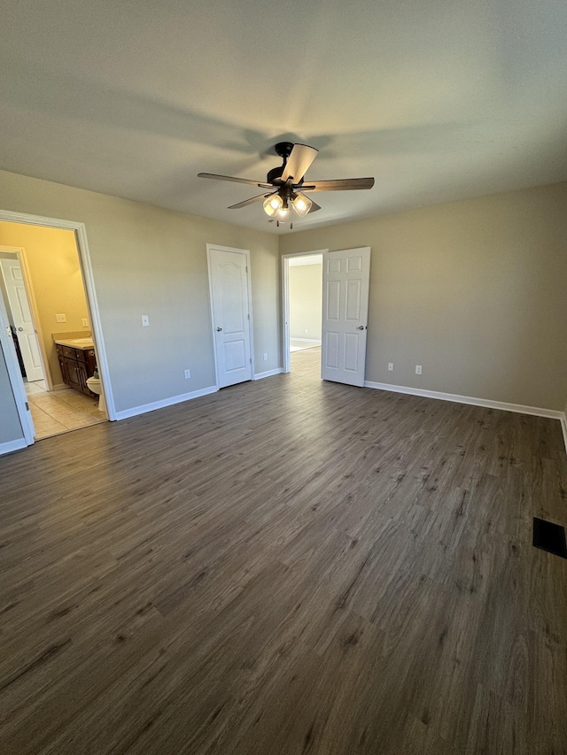 unfurnished bedroom with ceiling fan, connected bathroom, and dark hardwood / wood-style flooring